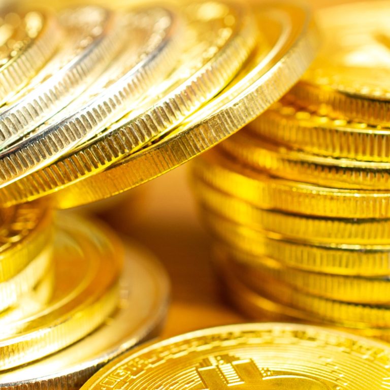 Goldene Münzenstapel, glänzend und dicht angeordnet.